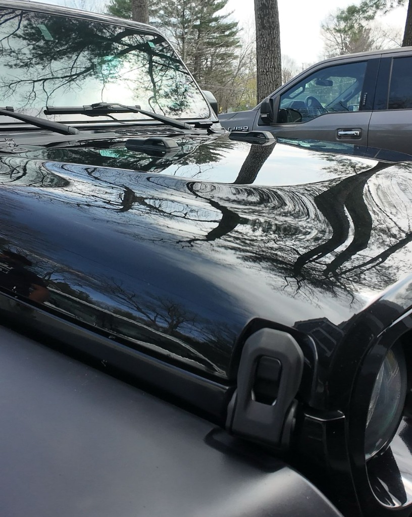 Mirror-finish black Jeep Wrangler after clay bar and premium hand wax treatment in North Ogden Utah